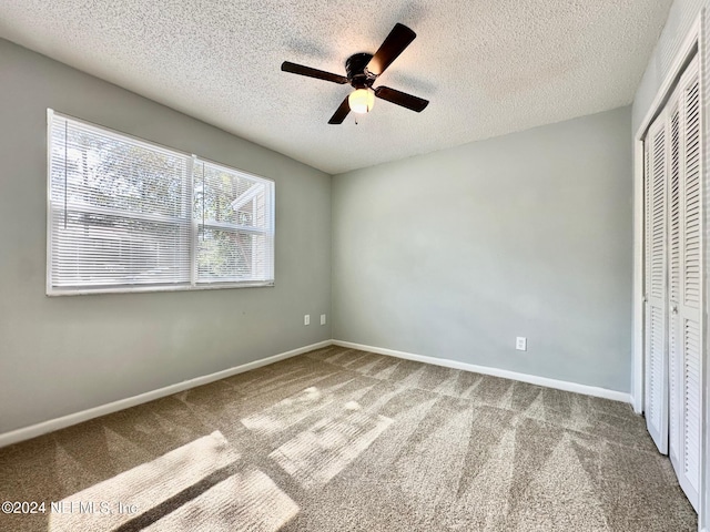 unfurnished bedroom with a textured ceiling, multiple windows, a closet, and ceiling fan