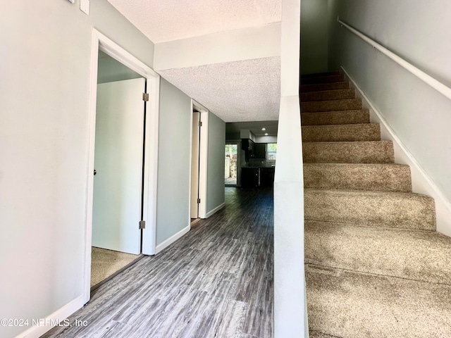 stairs featuring a textured ceiling and hardwood / wood-style floors