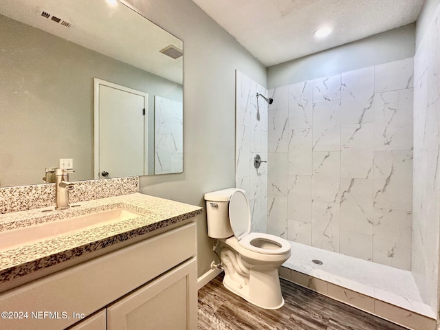 bathroom with vanity, tiled shower, wood-type flooring, and toilet