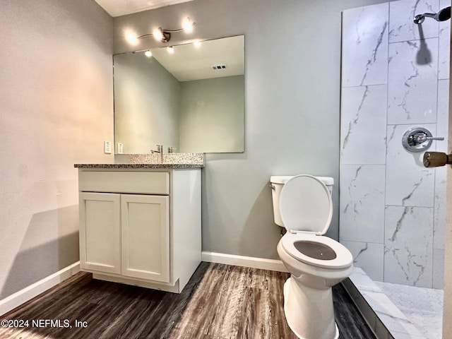 bathroom with vanity, tiled shower, hardwood / wood-style flooring, and toilet