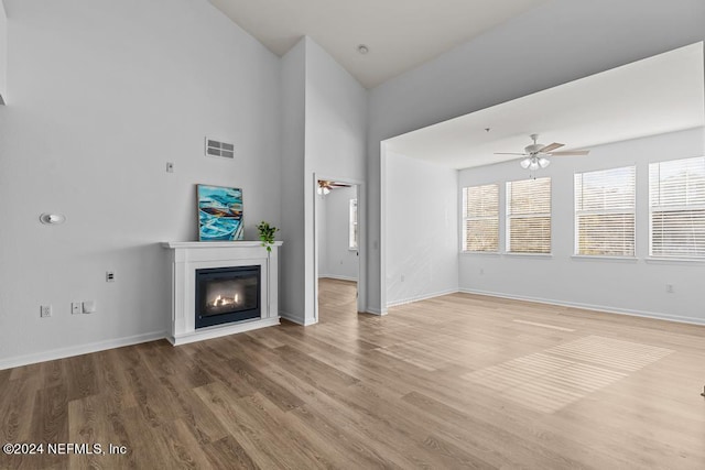 unfurnished living room featuring high vaulted ceiling, wood-type flooring, and ceiling fan