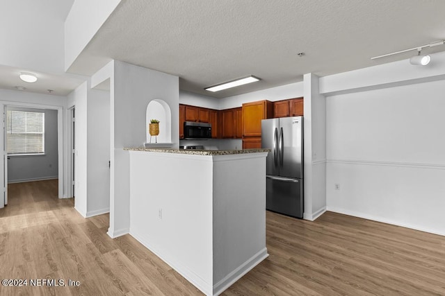 kitchen with appliances with stainless steel finishes, light hardwood / wood-style flooring, a textured ceiling, and rail lighting