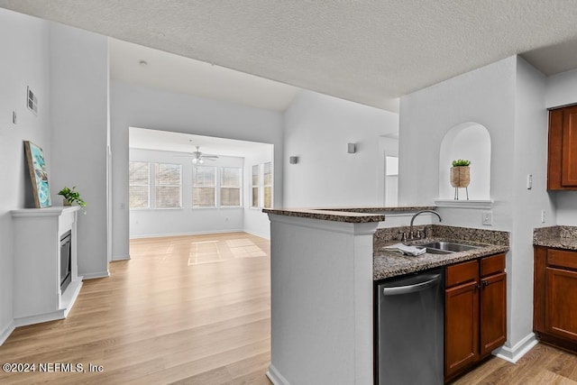 kitchen featuring dark stone counters, sink, stainless steel dishwasher, a textured ceiling, and light hardwood / wood-style floors