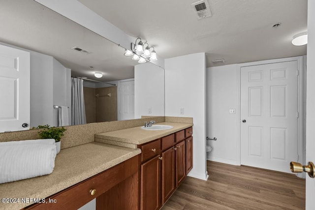 bathroom featuring toilet, hardwood / wood-style floors, curtained shower, and vanity