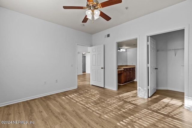 unfurnished bedroom featuring a walk in closet, ceiling fan, hardwood / wood-style flooring, connected bathroom, and a closet