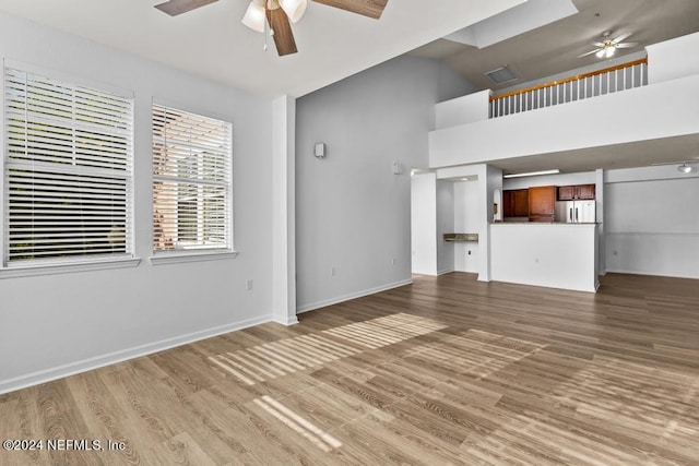 unfurnished living room with a high ceiling, hardwood / wood-style flooring, and ceiling fan