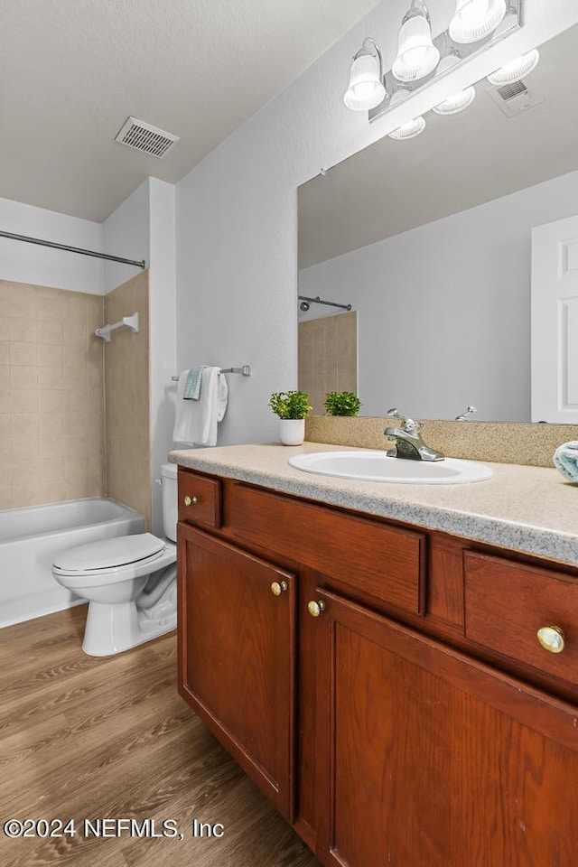 full bathroom featuring toilet, hardwood / wood-style floors, tiled shower / bath combo, and vanity