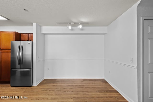 kitchen with stainless steel fridge, a textured ceiling, and light wood-type flooring