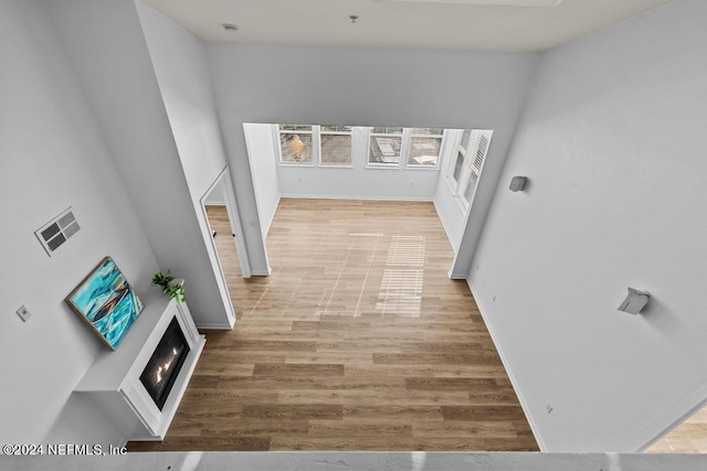 corridor featuring a towering ceiling and light wood-type flooring