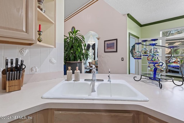 kitchen featuring light brown cabinets, tasteful backsplash, a textured ceiling, crown molding, and sink