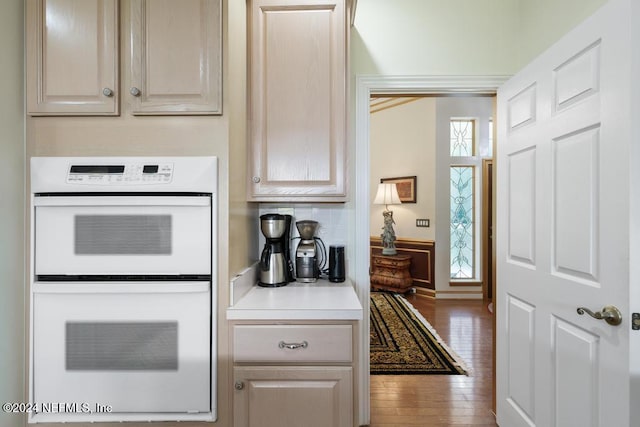 kitchen with light brown cabinets, wood-type flooring, and white double oven