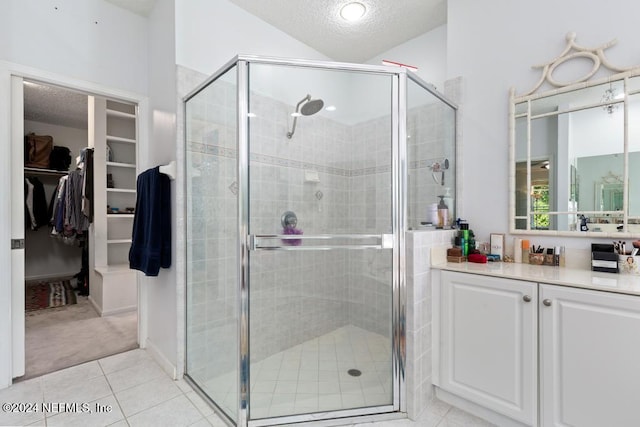 bathroom with lofted ceiling, a textured ceiling, vanity, an enclosed shower, and tile patterned flooring