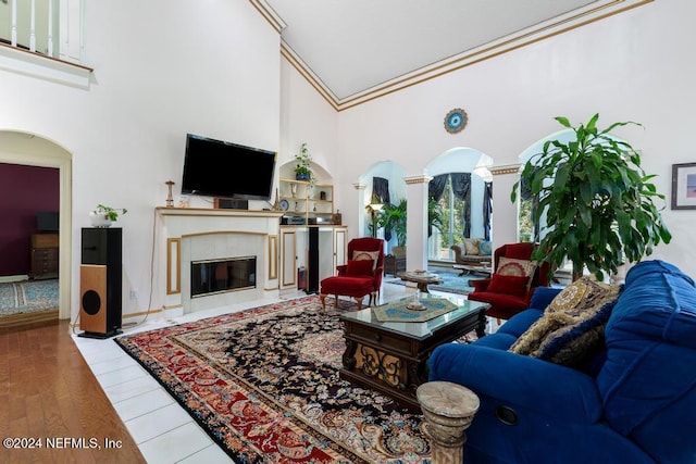 living room featuring high vaulted ceiling, ornamental molding, a tile fireplace, and hardwood / wood-style floors