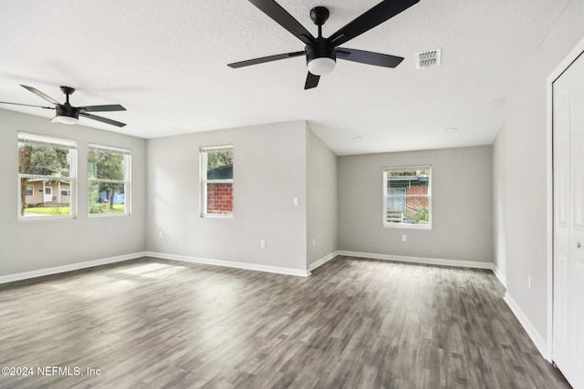 unfurnished room with a textured ceiling, dark wood-type flooring, and ceiling fan