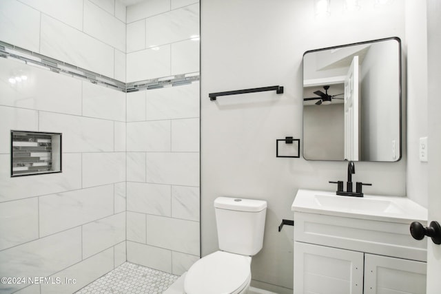 bathroom with vanity, a tile shower, and toilet