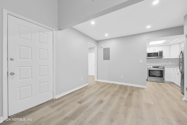 interior space featuring electric panel and light hardwood / wood-style flooring