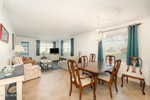 dining area with an inviting chandelier, light tile patterned floors, and a textured ceiling