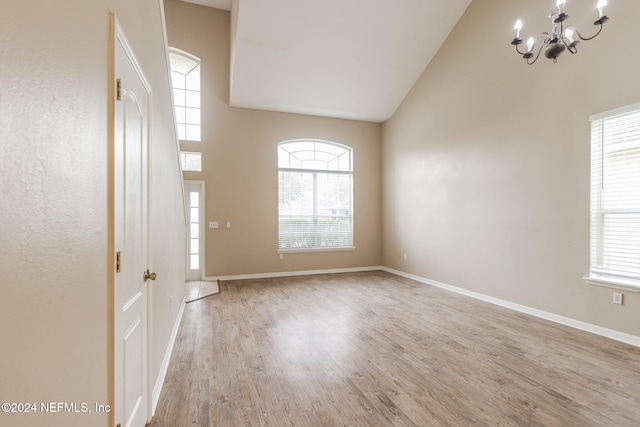 entrance foyer with high vaulted ceiling, light hardwood / wood-style floors, and an inviting chandelier