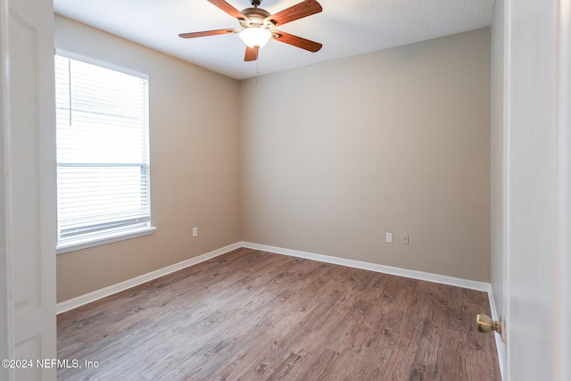 empty room with ceiling fan, wood-type flooring, and a textured ceiling