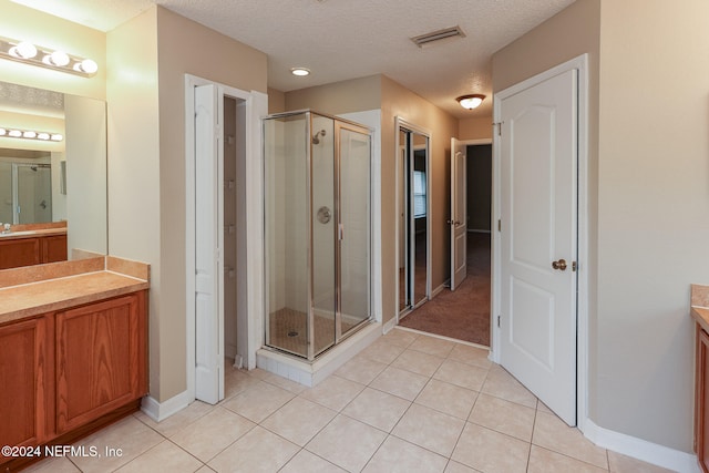 bathroom featuring tile patterned flooring, vanity, a textured ceiling, and a shower with shower door