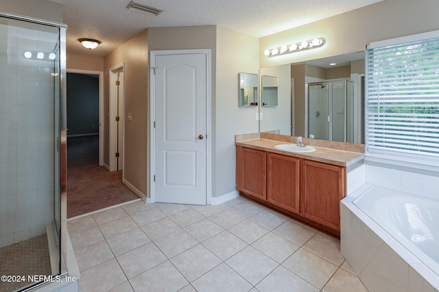 bathroom featuring independent shower and bath, vanity, a textured ceiling, and tile patterned floors