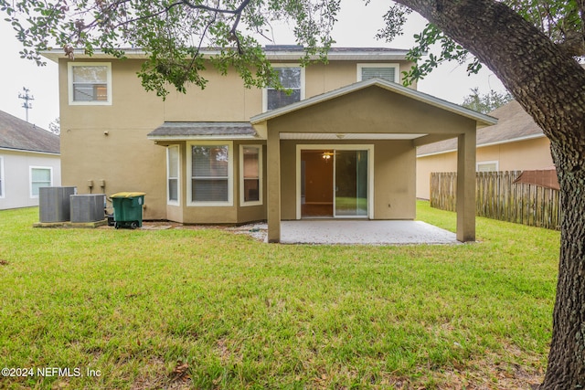 back of property with central AC, a lawn, and a patio