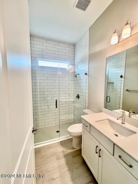 bathroom with vanity, toilet, and a shower with door