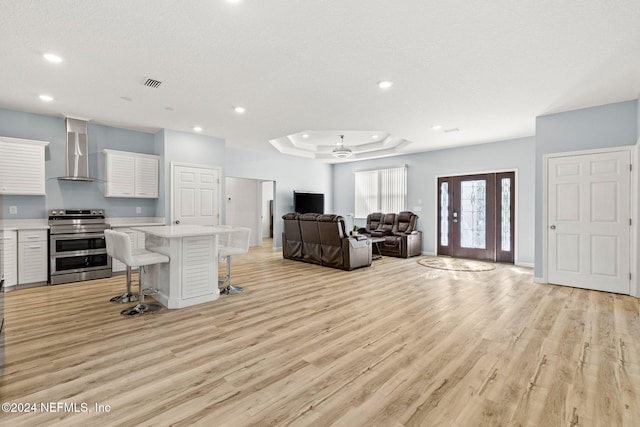 living room featuring light hardwood / wood-style floors, a textured ceiling, and a tray ceiling