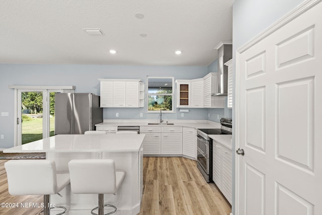 kitchen featuring stainless steel appliances, a breakfast bar, a kitchen island, and white cabinets