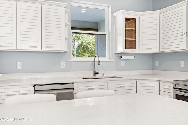 kitchen featuring white cabinetry, stainless steel appliances, light stone countertops, and sink