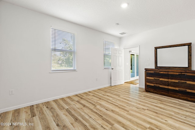 empty room with light hardwood / wood-style floors and a textured ceiling