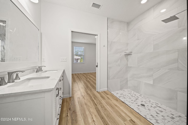 bathroom with vanity, hardwood / wood-style floors, a textured ceiling, and walk in shower