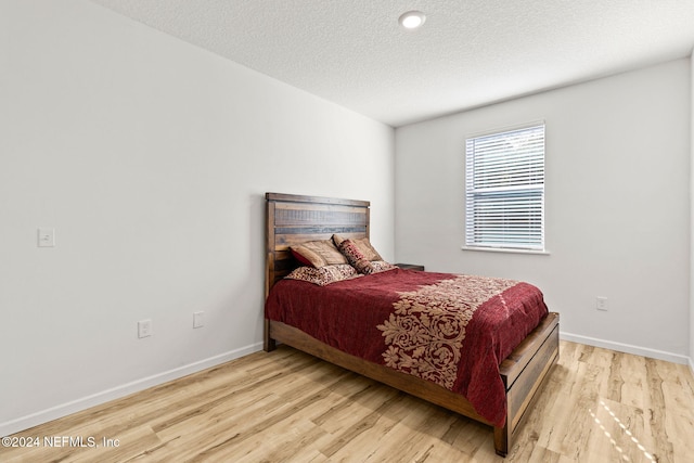 bedroom with a textured ceiling and light wood-type flooring