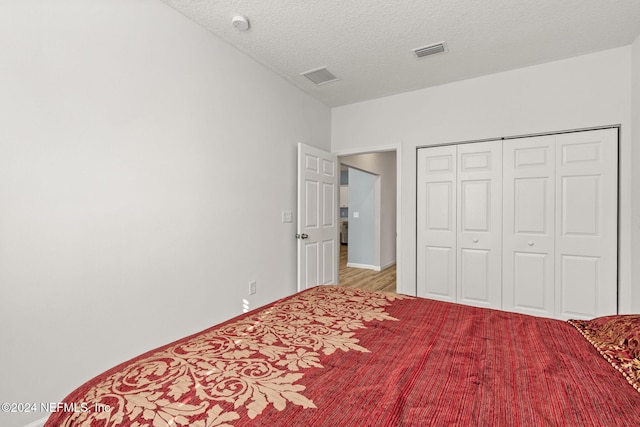 bedroom with light hardwood / wood-style flooring, a closet, and a textured ceiling