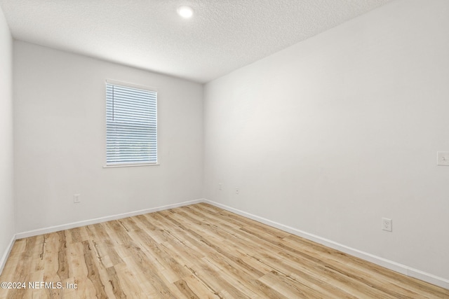 spare room featuring light hardwood / wood-style flooring and a textured ceiling