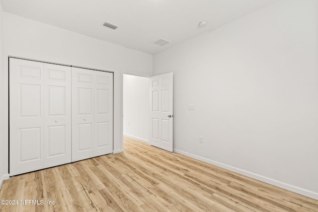 unfurnished bedroom with a closet, a textured ceiling, and light hardwood / wood-style flooring