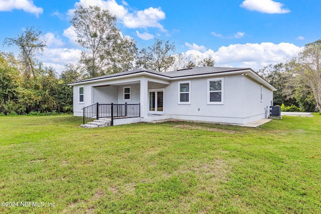 rear view of property featuring central AC and a lawn