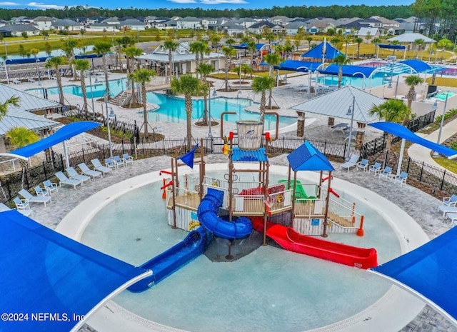 community play area featuring a water play area, fence, and a community pool