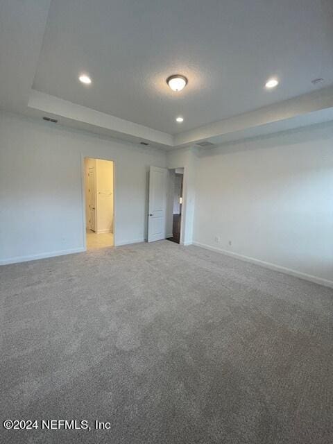 unfurnished bedroom featuring carpet flooring and a tray ceiling