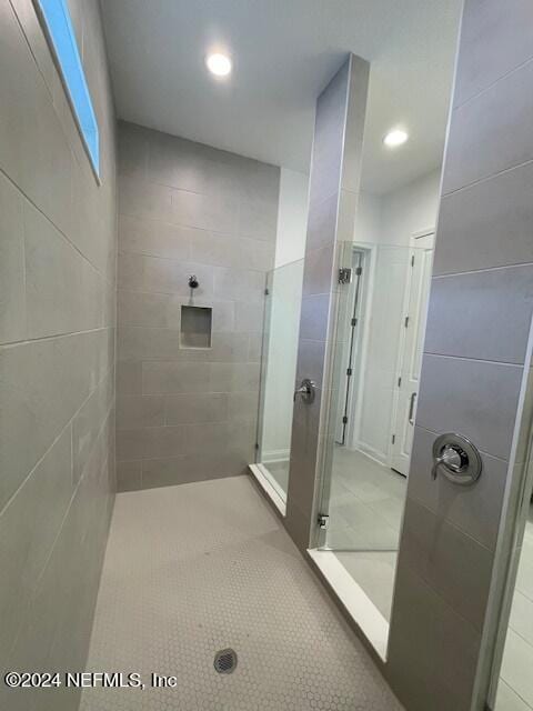 bathroom with a shower with door and tile patterned floors