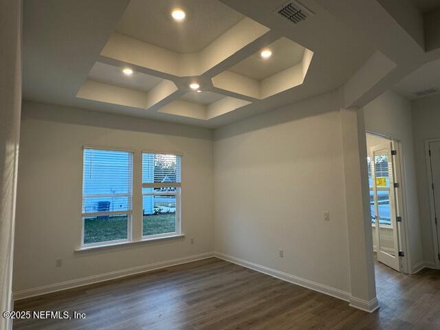 empty room with dark hardwood / wood-style flooring and coffered ceiling