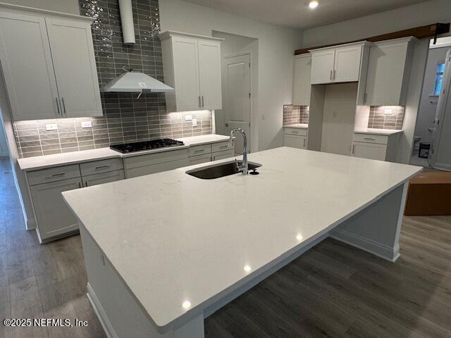 kitchen featuring sink, black gas stovetop, and a center island with sink