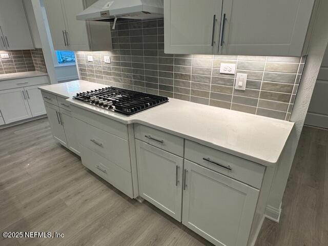 kitchen with white cabinetry, decorative backsplash, light hardwood / wood-style flooring, and stainless steel gas stovetop