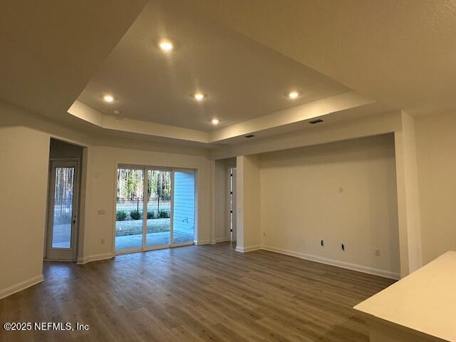 unfurnished room featuring dark hardwood / wood-style flooring and a tray ceiling