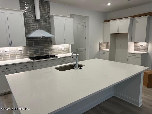 kitchen with sink, dark hardwood / wood-style floors, stainless steel gas cooktop, and white cabinets