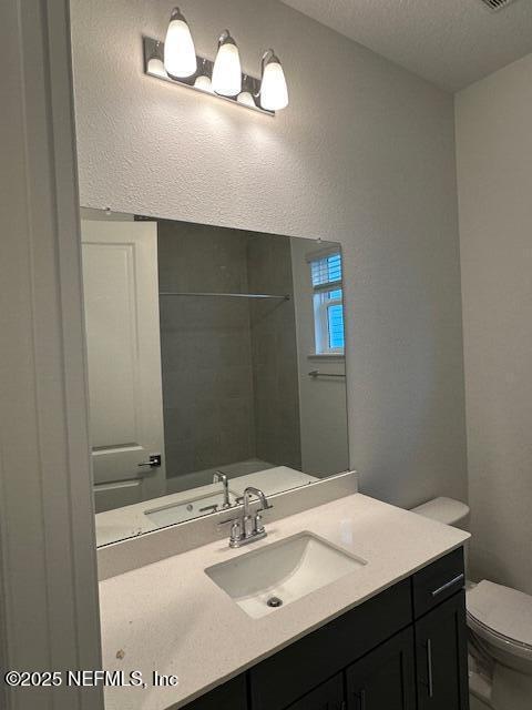 bathroom with vanity, a textured ceiling, toilet, and walk in shower