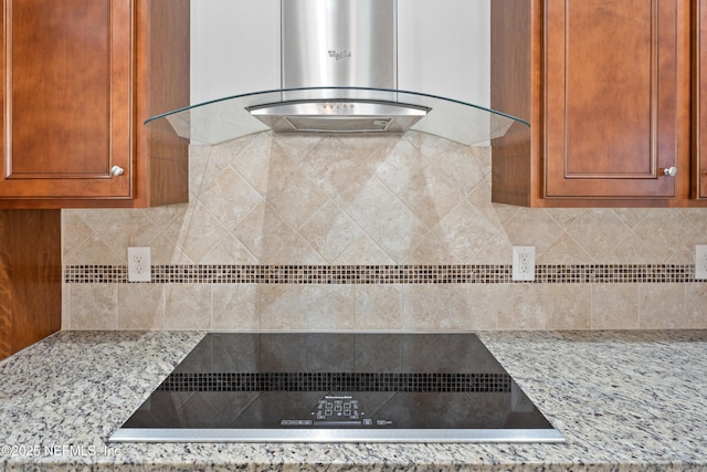 kitchen featuring backsplash, light stone countertops, wall chimney range hood, and black electric stovetop