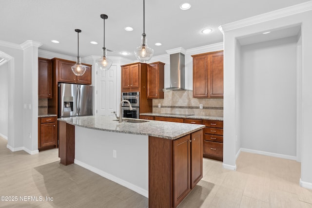 kitchen featuring light stone countertops, pendant lighting, appliances with stainless steel finishes, wall chimney range hood, and a center island with sink