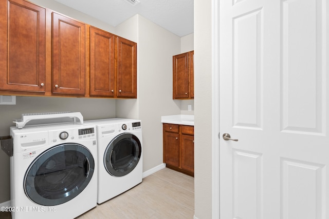 laundry area featuring cabinets, light tile patterned flooring, and washing machine and clothes dryer