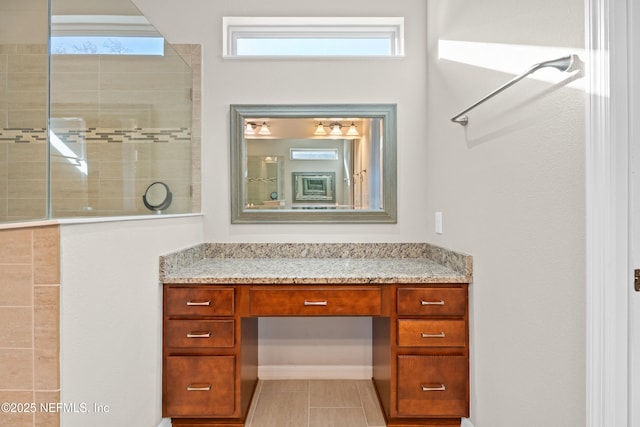 bathroom featuring vanity, tile patterned flooring, and a tile shower